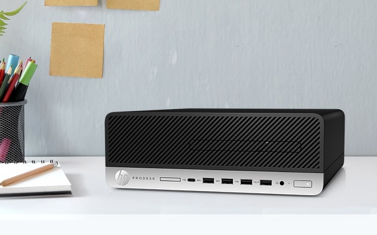 An HP ProDesk 600 G4 Small Form Factor PC placed horizontally on a desk, with notebook, mesh pencil holder on the left